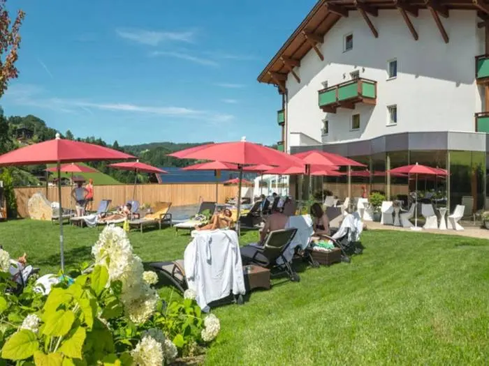Ligweide met rode parasols in de tuin van Hotel Wastlhof