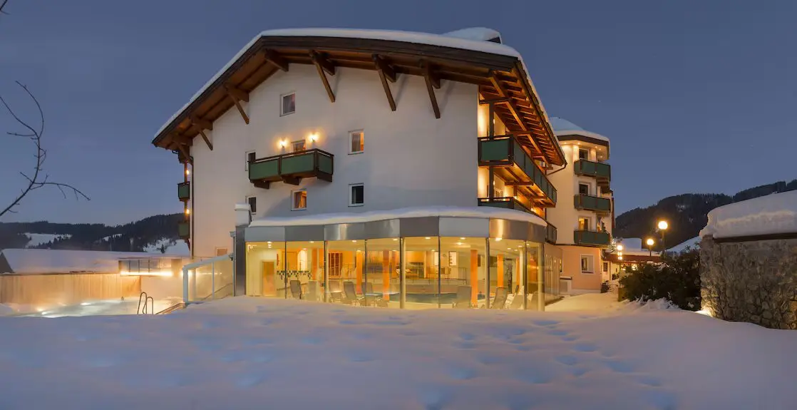 Wellnessvleugel van Hotel Wastlhof met glazen serre en verlicht buitenzwembad in de sneeuw