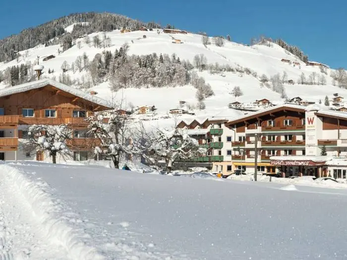 Hotel Wastlhof op een zonnige winterdag met besneeuwde hellingen erachter