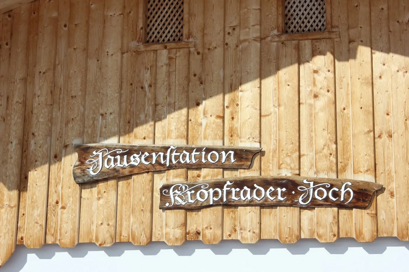 Wooden façade with two wooden signs reading ‘Jausenstation Kröpfrader Joch’