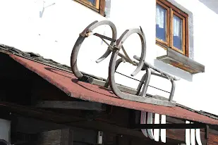 Wrought-iron ornament on the roof of a white house façade with wooden windows
