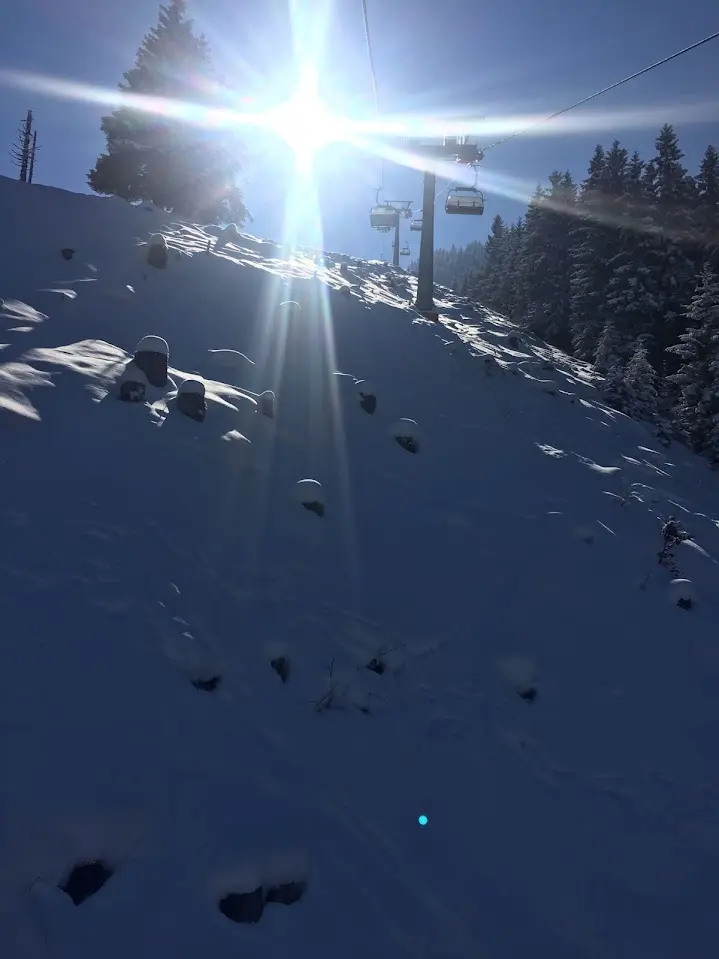 Chairlift above a snowy slope in bright backlight