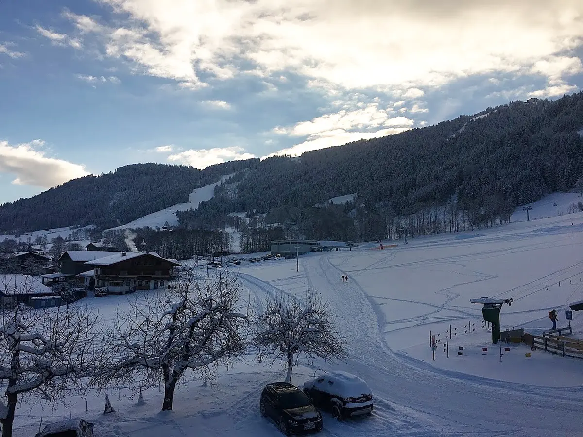 Uitzicht op de besneeuwde pistes en liften van Niederau bij winterzon