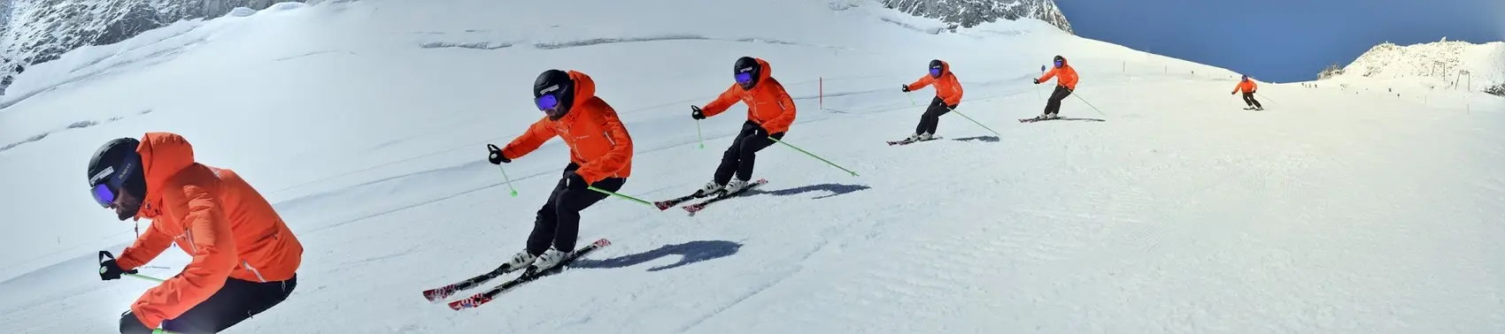 Sequence of a skier in an orange jacket carving a turn on a wide, sunny glacier slope