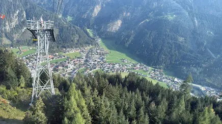 View from a cable car past a pylon down to a village in a green mountain valley