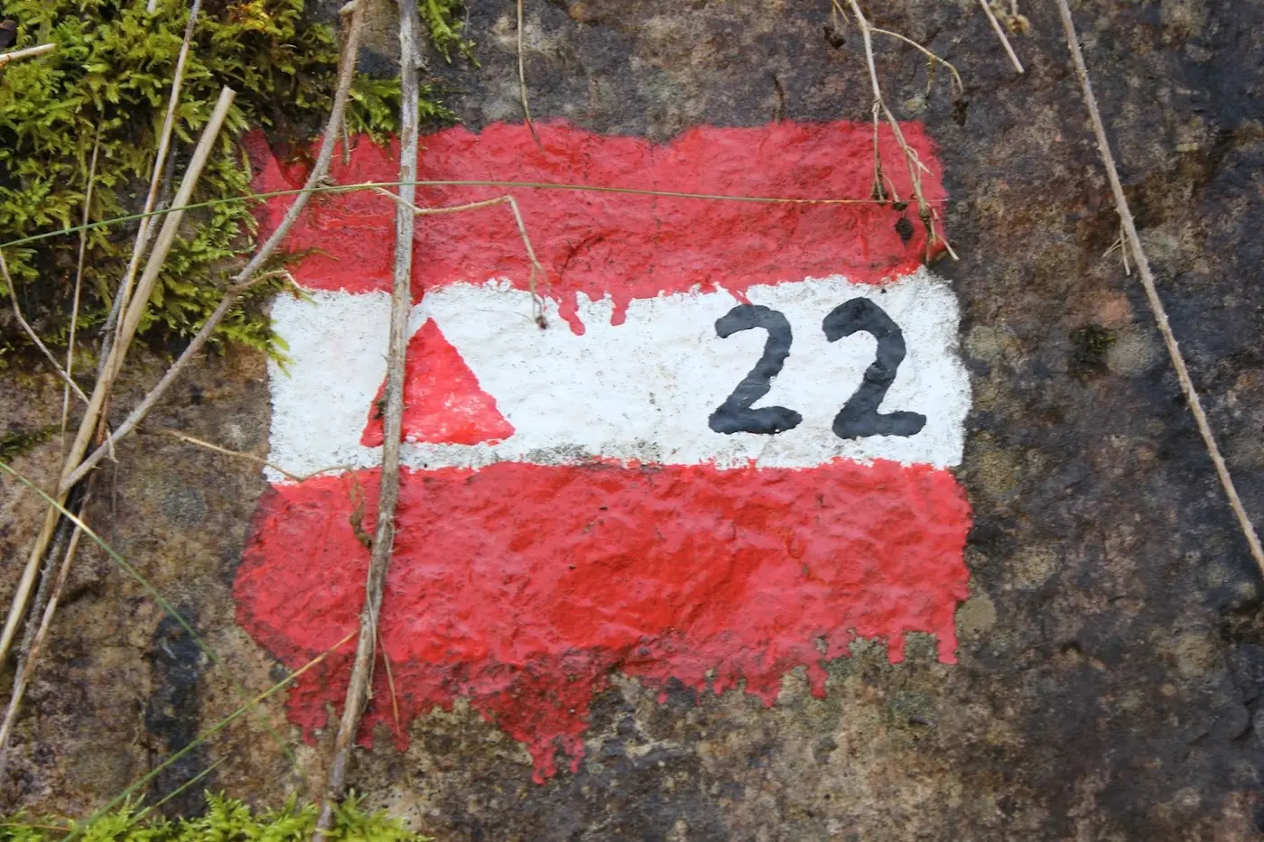 Red-white-red hiking marker with a triangle and the number 22, painted on a rock