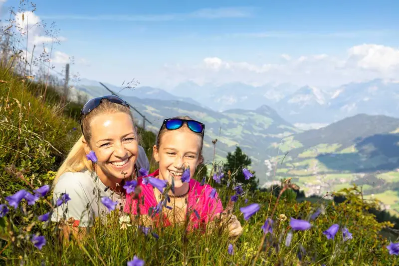 Twee wandelaars tussen paarsblauwe bloemen op een bergweide