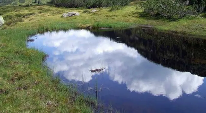 Klein bergmeertje met weerspiegelende wolken tijdens een wandeling