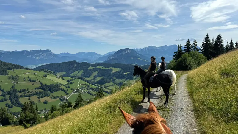 Ruiters op een bergpad met uitzicht over de weiden van de Wildschönau