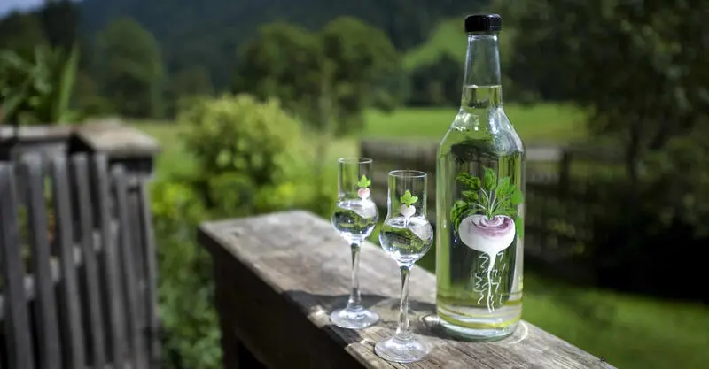 Fles Wildschönauer Krautinger met twee glaasjes op een houten balustrade